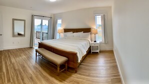 A bedroom with a large bed, a bench, a nightstand, and a mirror.