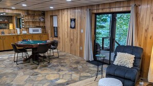 Een gezellige kamer met een pooltafel, comfortabele zithoek, een bar en uitzicht op het omliggende landschap.