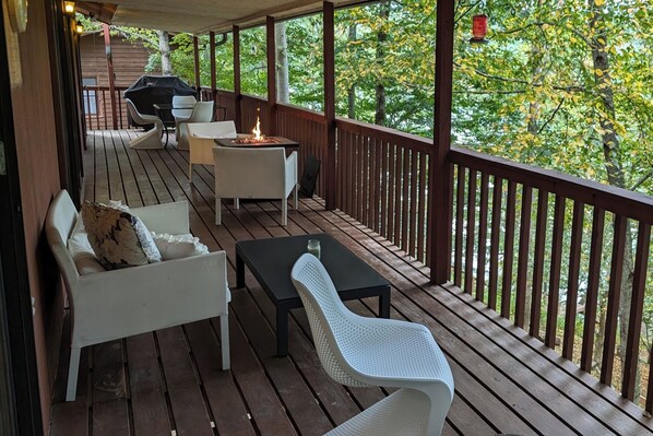 Eine Holzterrasse mit Gartenmöbeln, darunter eine Sitzecke mit Sofa und Stühlen, sowie ein Tisch mit Feuerstelle.
