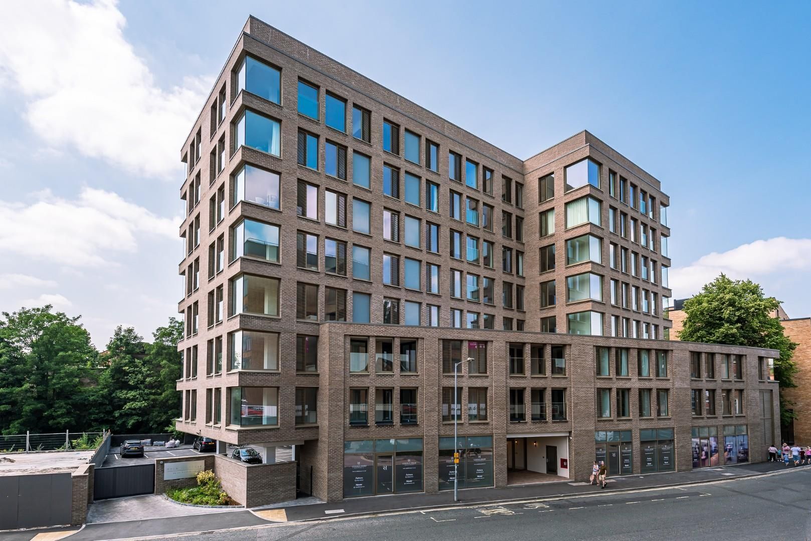 A multi-story building with a brick facade, large windows, and a flat roof.