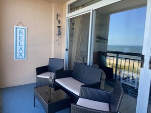A balcony with wicker furniture, a glass door, and a 'RELAX' sign.
