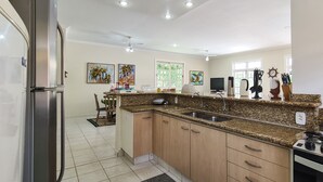 A modern kitchen with granite countertops, stainless steel appliances, and wooden cabinets. - Casa Amarela - Riviera (Bertioga)