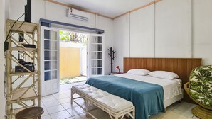 A bedroom with a bed, a bench, a chair, and a wardrobe. - Casa Amarela - Riviera (Bertioga)
