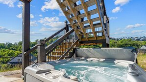Een hottub met een houten terras en een trap naar een overdekt gedeelte.