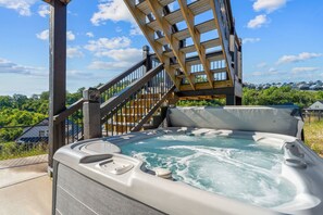A hot tub with a wooden deck and stairs leading to a covered area. - Private Putting Green Retreat with Firepit, Hot Tub, Free Tickets, Views & Community Indoor Pool (Branson)