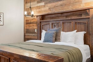 A bed with a wooden headboard, a bedside table, and a hanging light fixture. - Private Putting Green Retreat with Firepit, Hot Tub, Free Tickets, Views & Community Indoor Pool (Branson)