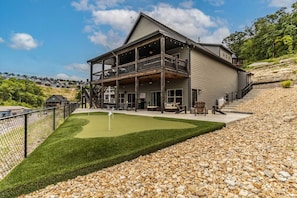 A two-story building with a balcony, a covered patio area, and a well-maintained lawn.