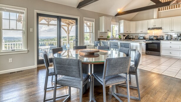 A spacious kitchen with white cabinets, a large island with chairs, and a view through the open sliding doors. - 5BR Farmhouse☆King Size Bed☆Mountain View☆28 Acres (Ancramdale)