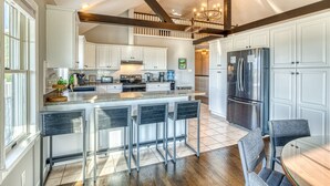 A spacious kitchen with white cabinetry, a large island with bar stools, and a stainless steel refrigerator. - 5BR Farmhouse☆King Size Bed☆Mountain View☆28 Acres (Ancramdale)