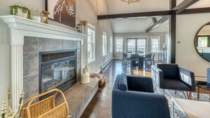 A spacious living room with a fireplace, modern furniture, and large windows offering views of the city. - 5BR Farmhouse☆King Size Bed☆Mountain View☆28 Acres (Ancramdale)