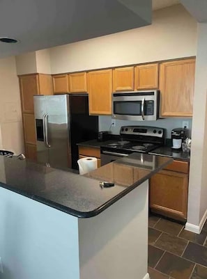 Una cocina moderna con armarios de madera, electrodomésticos de acero inoxidable y una isla con encimera negra.