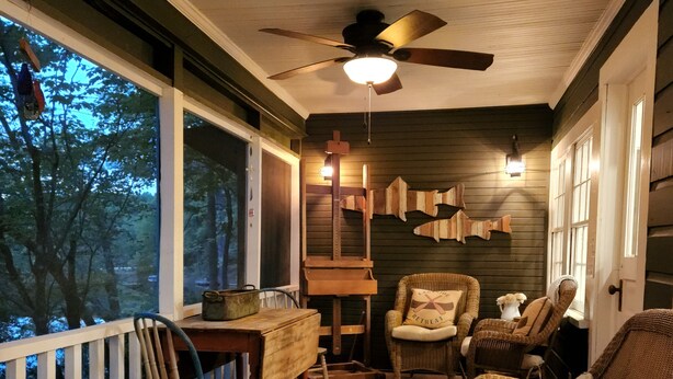 A cozy porch with wicker furniture, a ceiling fan, and a view of the outdoors.