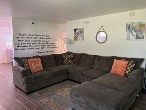 Un soggiorno moderno con un divano componibile, un tappeto decorativo e opere d'arte a parete.