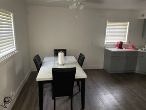 A dining area with a table and chairs, a ceiling fan, and a kitchen area with cabinets and a countertop. - Lovely 1 bed room apartment, all to yourself. (Merrillville)