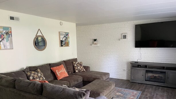 Ein Wohnzimmer mit Ecksofa, Flachbildfernseher, Kamin und einem gemusterten Teppich.
