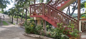 A staircase with a wooden railing, surrounded by greenery and flowers.