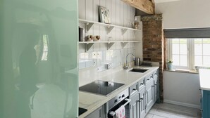 Una cocina con armarios blancos, un lavamanos de acero inoxidable y un refrigerador de estilo vintage.
