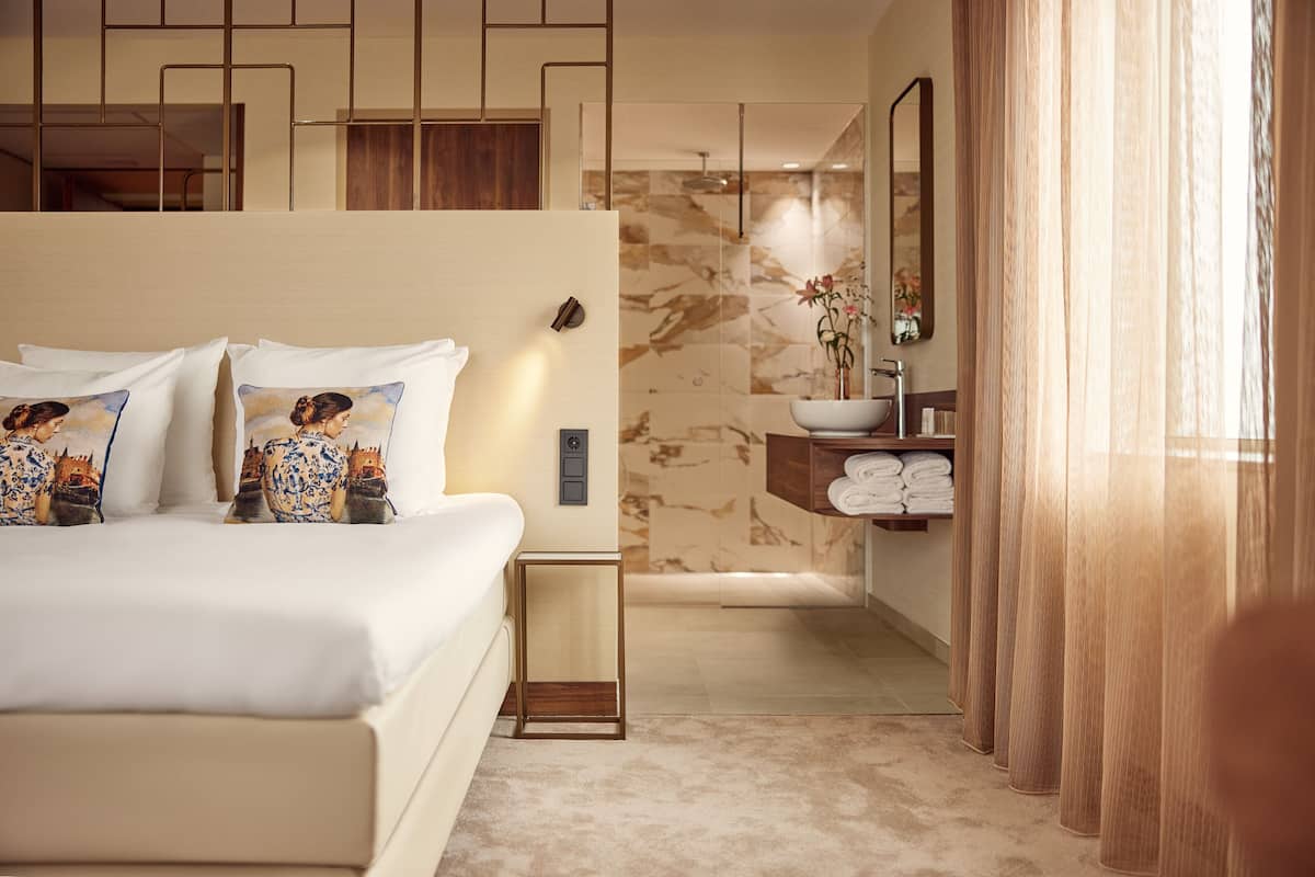 Een moderne hotelkamer met een groot bed, een badkamer met een marmeren wand en een houten opbergmeubel.