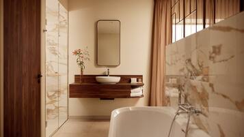 Une salle de bain moderne avec un mur en marbre, une baignoire blanche, un meuble-lavabo en bois et un grand miroir.