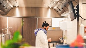 A modern kitchen with stainless steel appliances, a person preparing food, and a blue bowl on the counter.