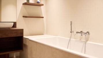 A modern bathroom with a freestanding bathtub, wooden shelves, and a white basin.