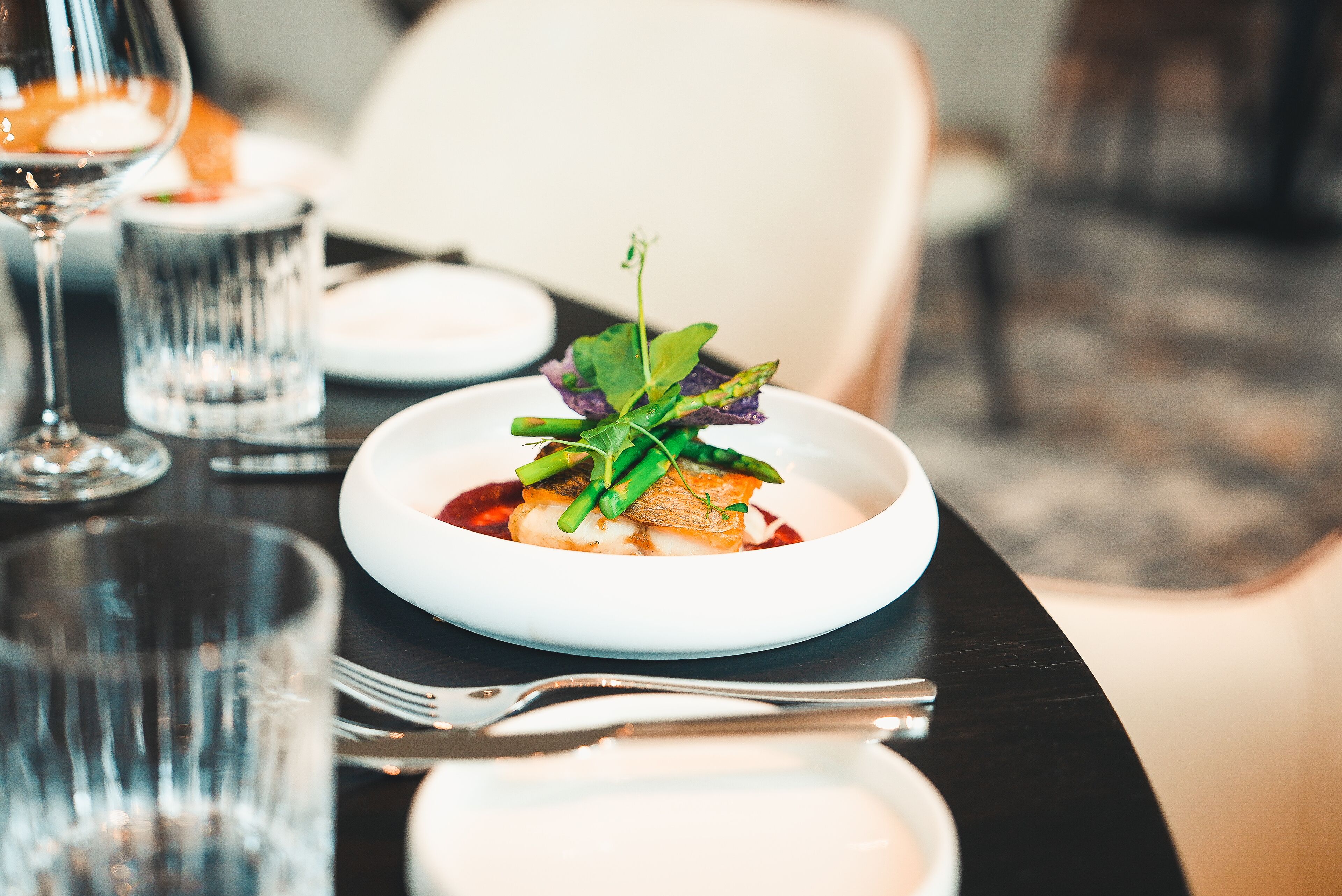 A well-set dining table with a white plate, a glass of water, and a fork.