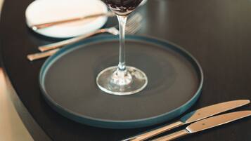 A dessert in a martini glass on a table with a dark tablecloth, silverware, and a white plate.