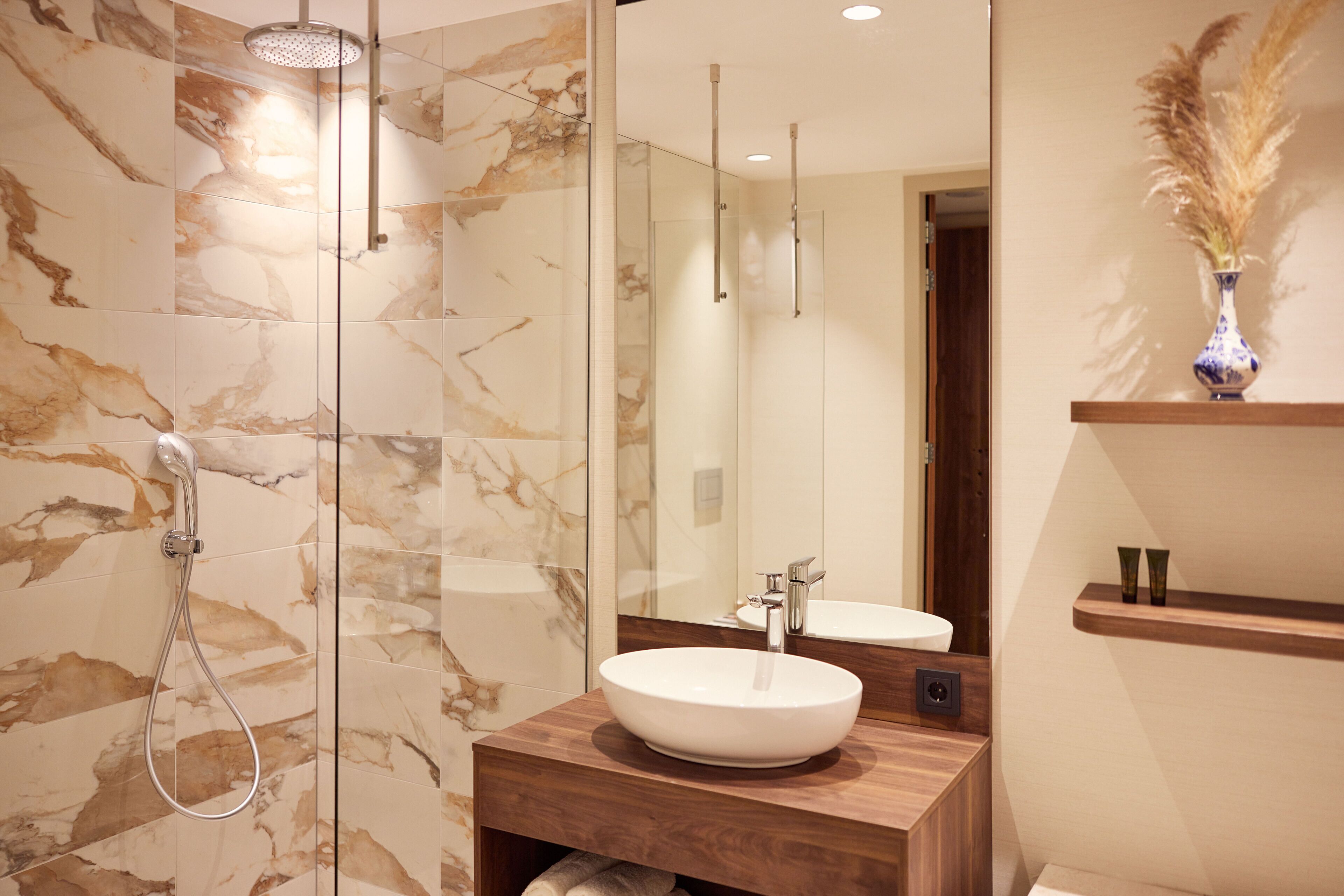 A modern bathroom with a glass-enclosed shower, a wooden vanity with a white sink, and a mirror above the sink.