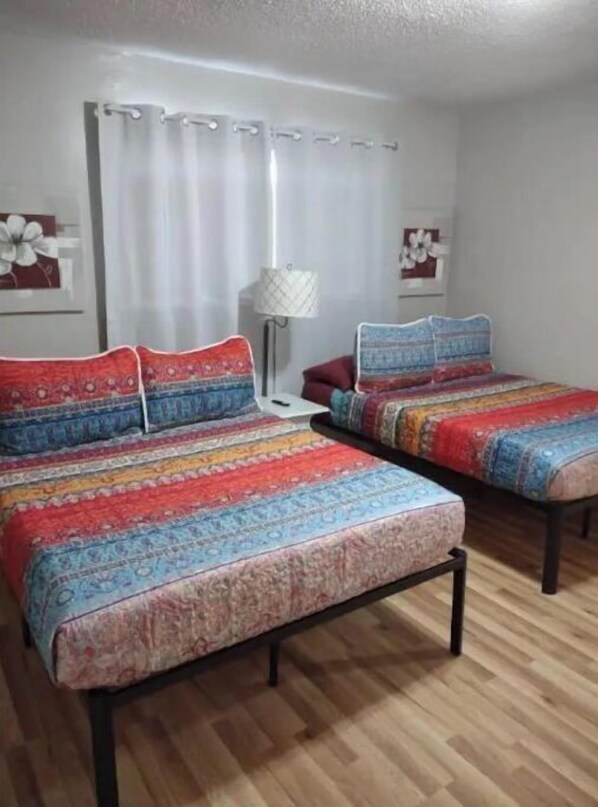 A bedroom with two beds, a nightstand, and a lamp. - Close to Downtown, Restaurants , Events ,Beaches and Naval Base! (Pensacola)