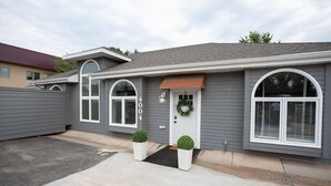 A two-story house with a grey exterior, white trim, and a front door with a wreath.