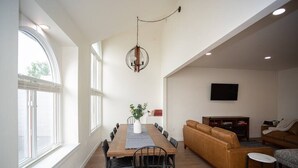 A dining area with a long wooden table, black chairs, and a hanging light fixture.