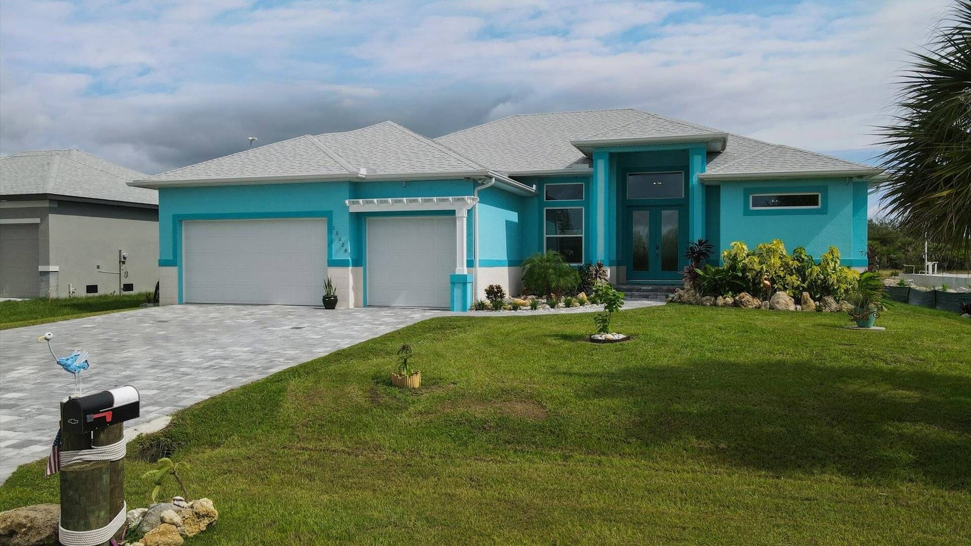 A modern two-story house with a blue exterior, a garage, and a well-maintained lawn.
