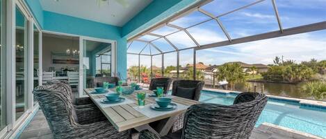 Un patio cubierto con piscina, mobiliario de mimbre y vistas del paisaje circundante.