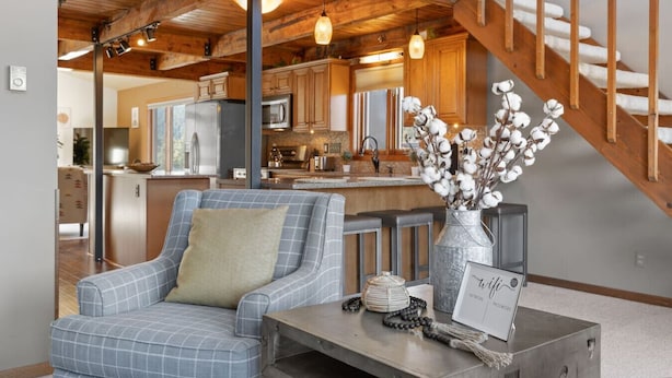 A living room with a plaid sofa, a coffee table, a vase with cotton branches, and a sign reading "wifi".