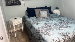 Een slaapkamer met een bed, nachtkastje, ladekast en een wanddecoratie waarop de fases van de maan staan afgebeeld.