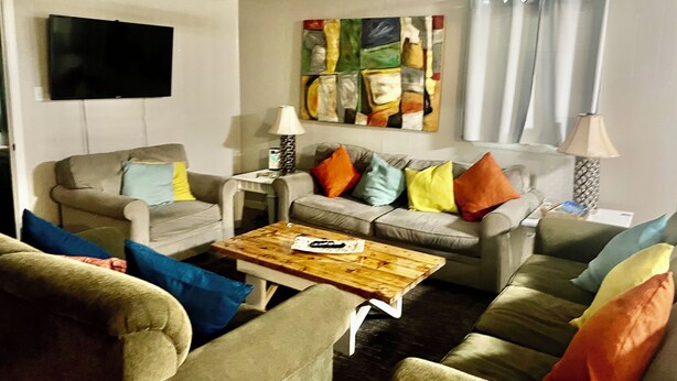 Een woonkamer met twee banken, een salontafel, een televisie en een schilderij aan de muur.
