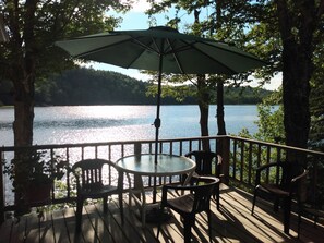 A deck with a table and chairs, overlooking a lake.