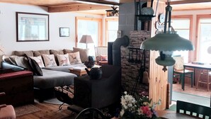 Een gezellige woonkamer met een stenen open haard, een bank en een eettafel met stoelen.