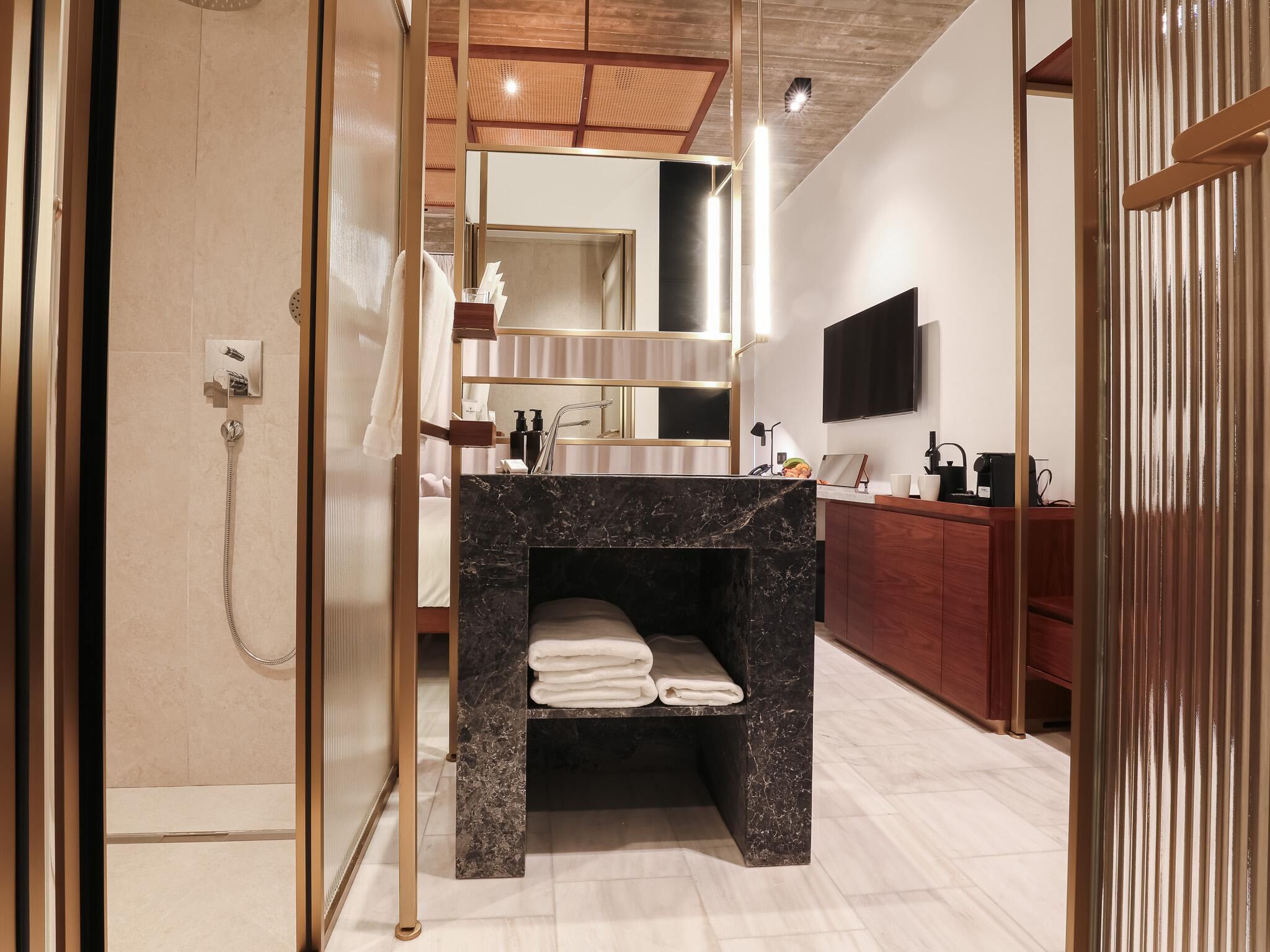 A modern bathroom with a marble sink, a shower, and a vanity with a mirror.