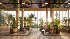 Un espacio interior amplio con ventanas grandes, arreglos de asientos y plantas en macetas.