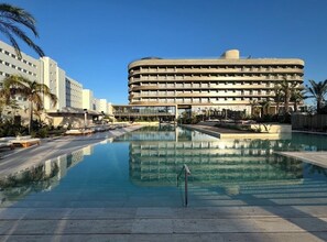 A hotel with a large pool, multiple floors, and a modern architectural design. - The Nines (Ayia Napa)