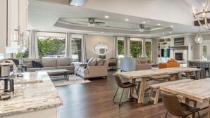 A spacious kitchen with a large island, modern appliances, and a dining area with wooden tables and chairs.