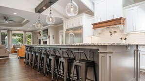A modern kitchen with a central island, bar stools, and a large window.