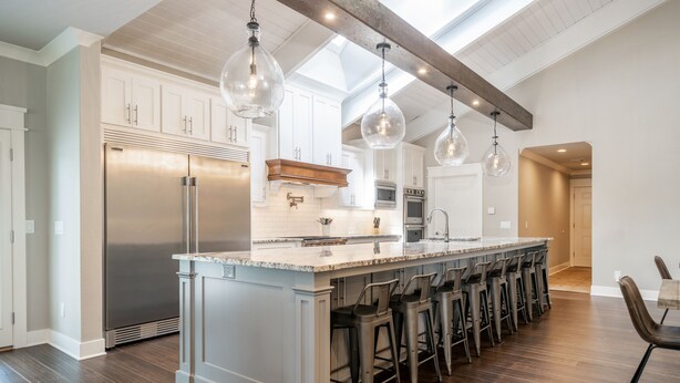 A spacious kitchen with a central island, stainless steel appliances, and hanging pendant lights.