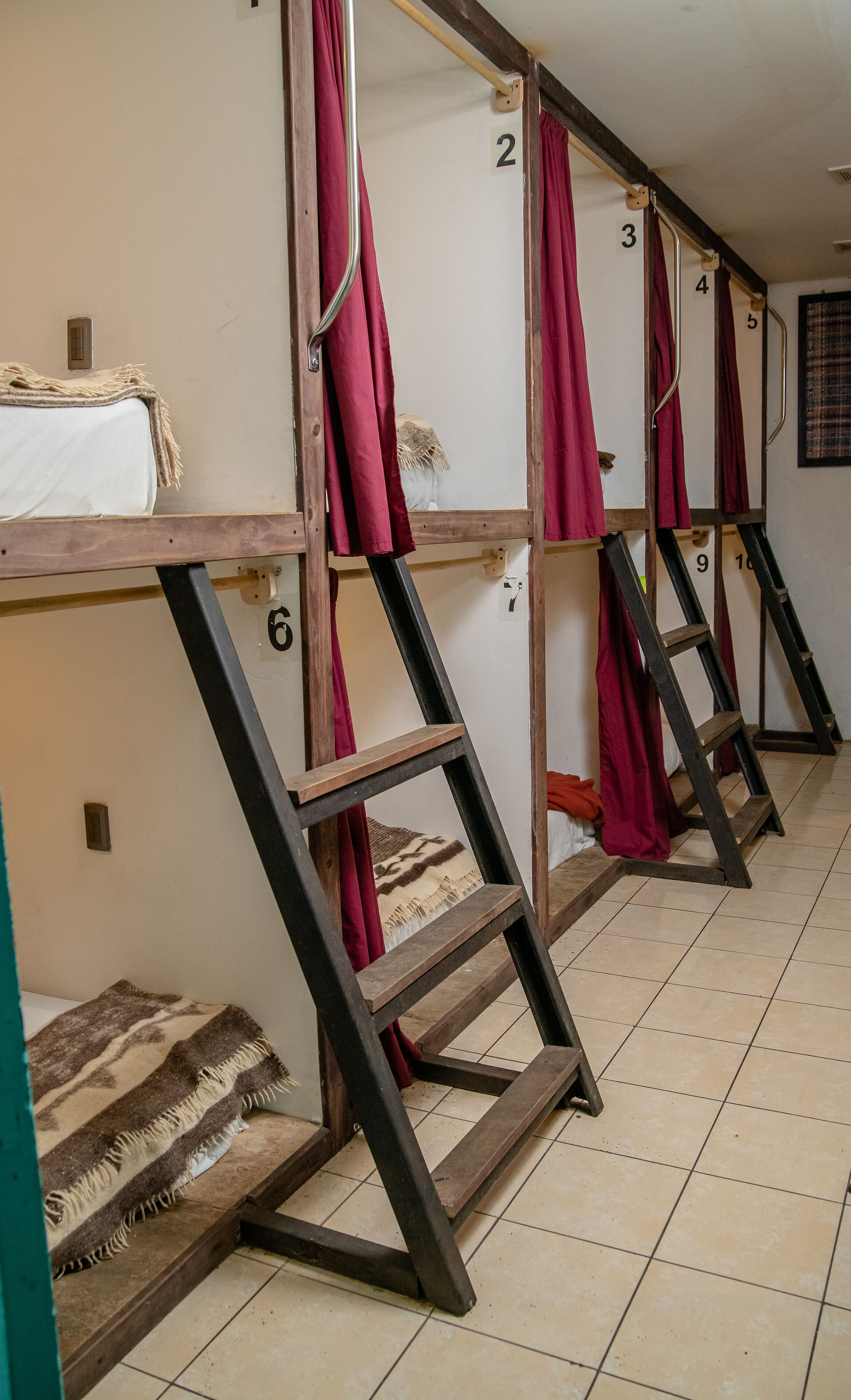Bunk beds with numbers on the wall, a tiled floor, and a blanket on one bed.