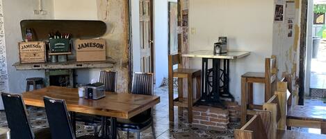 Un espace repas comprenant une table et des chaises en bois, un sol carrelé et un plafond rustique avec des poutres apparentes.