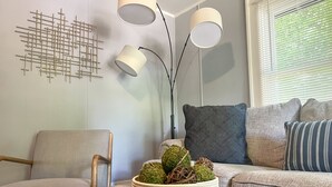 A modern living room with a wooden coffee table, a grey sofa with patterned cushions, a decorative wall piece, and a floor lamp. - NEW! Modern & Cozy close to Downtown Attractions! (Hot Springs)