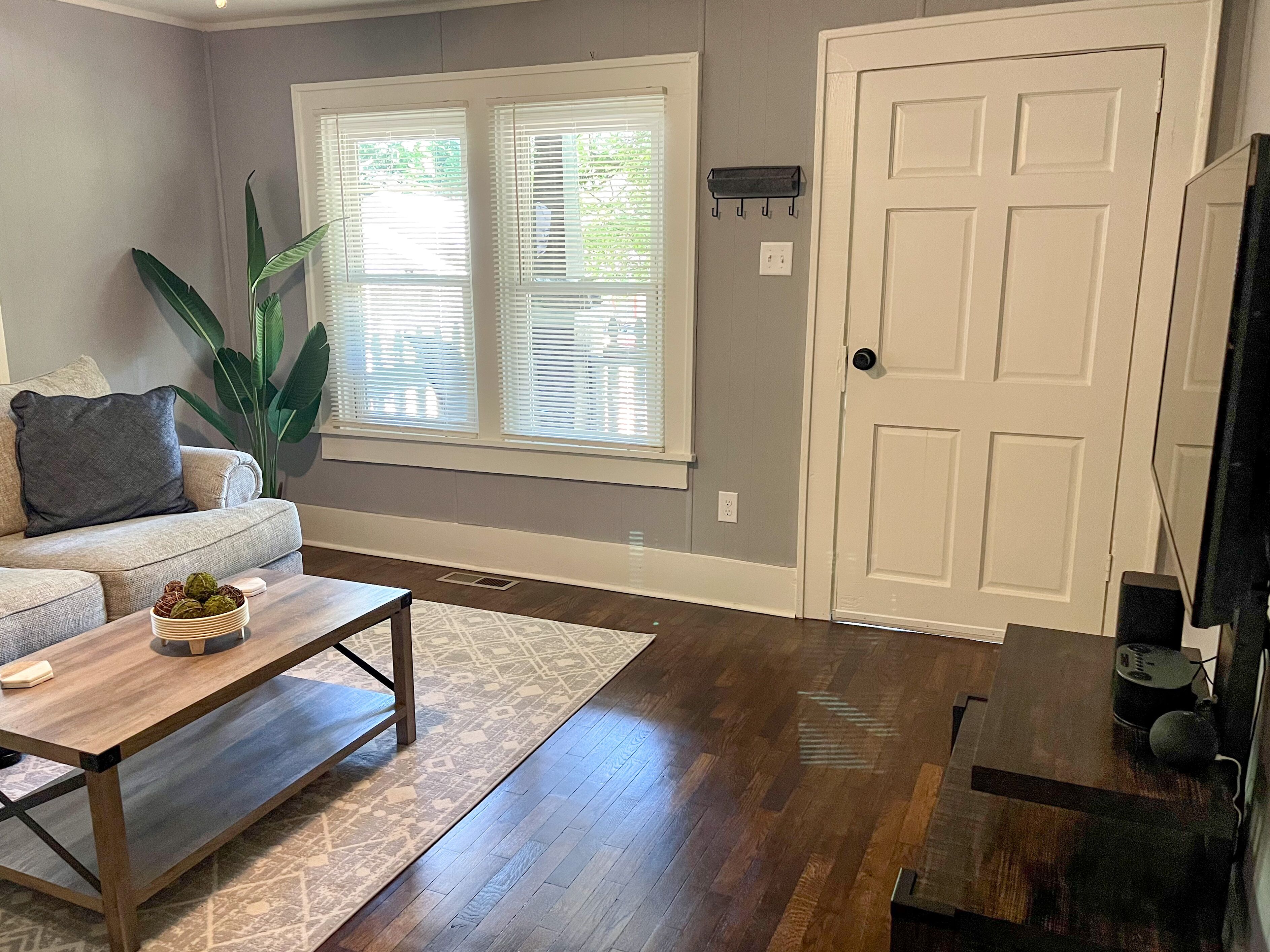 A living room with a sofa, coffee table, and a large window with blinds.