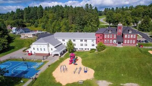 A large building with multiple sections, including a playground with a slide and swings, a basketball court, and a tennis court. - The Homestead - Walk to village, bring the pup! (Johnson)