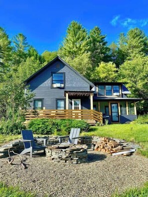 Une maison à deux étages avec une terrasse et un espace aménagé pour un foyer extérieur.